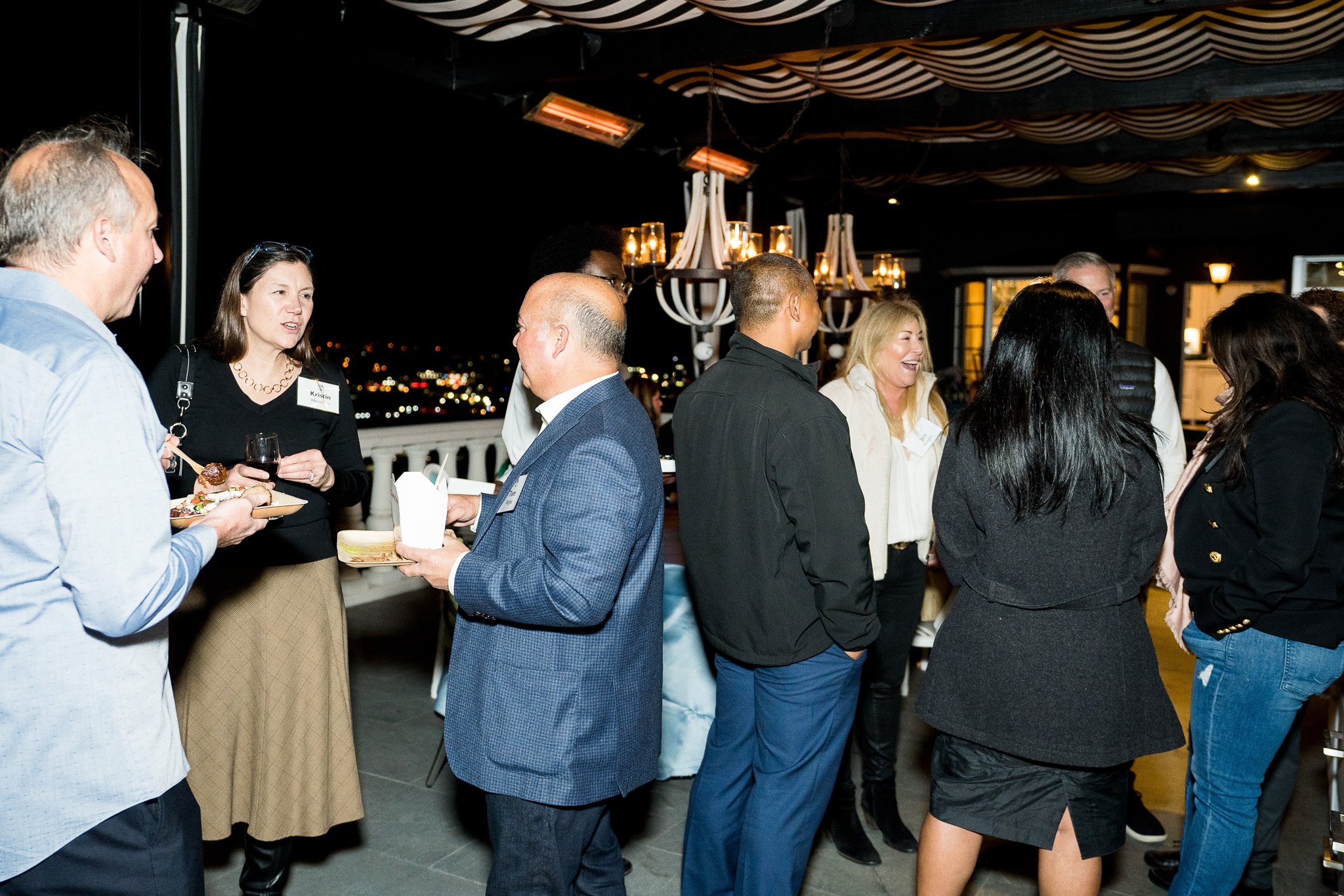 An evening event where a group of professionally dressed people are engaged in conversation