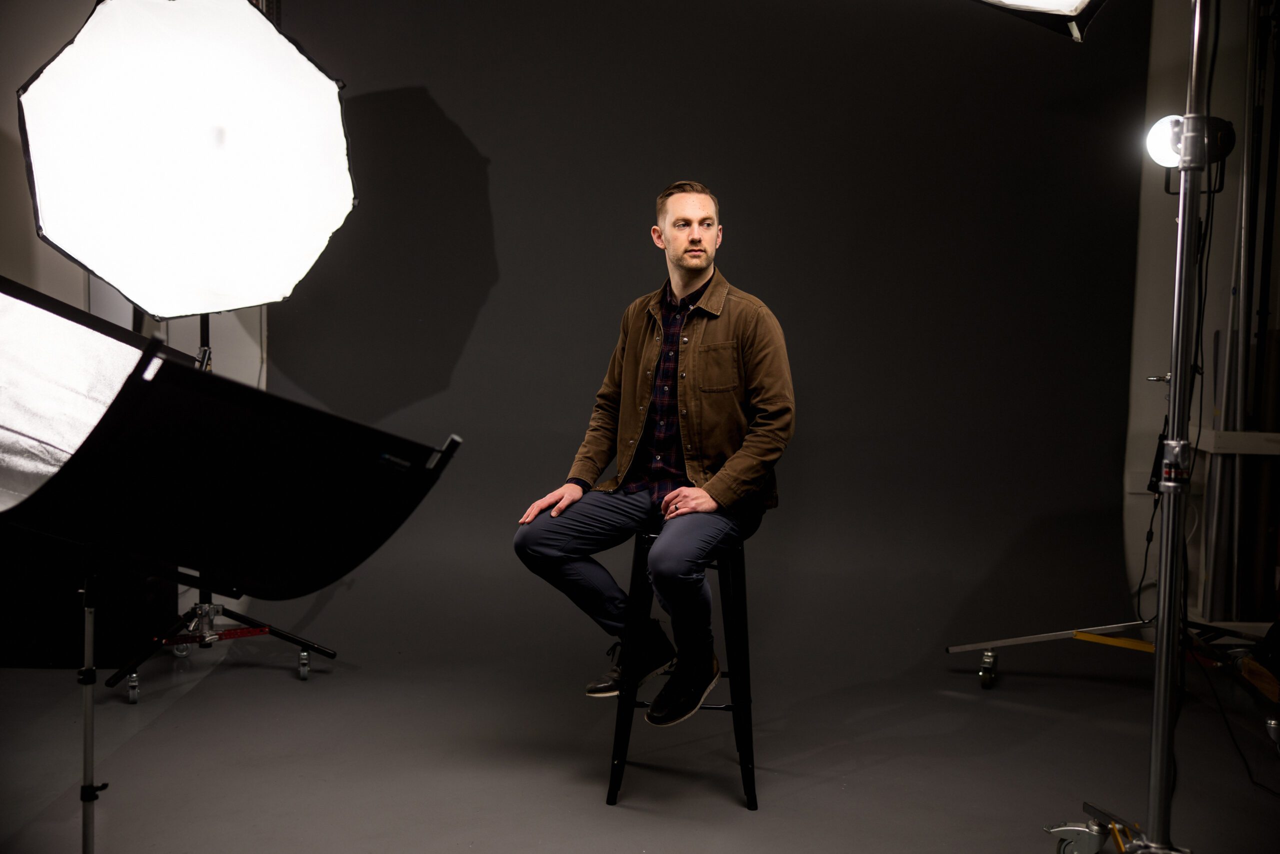 A man sitting on a stool, illuminated by a soft light