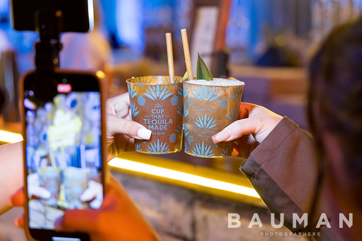 A person photographing a colorful drink with a smartphone
