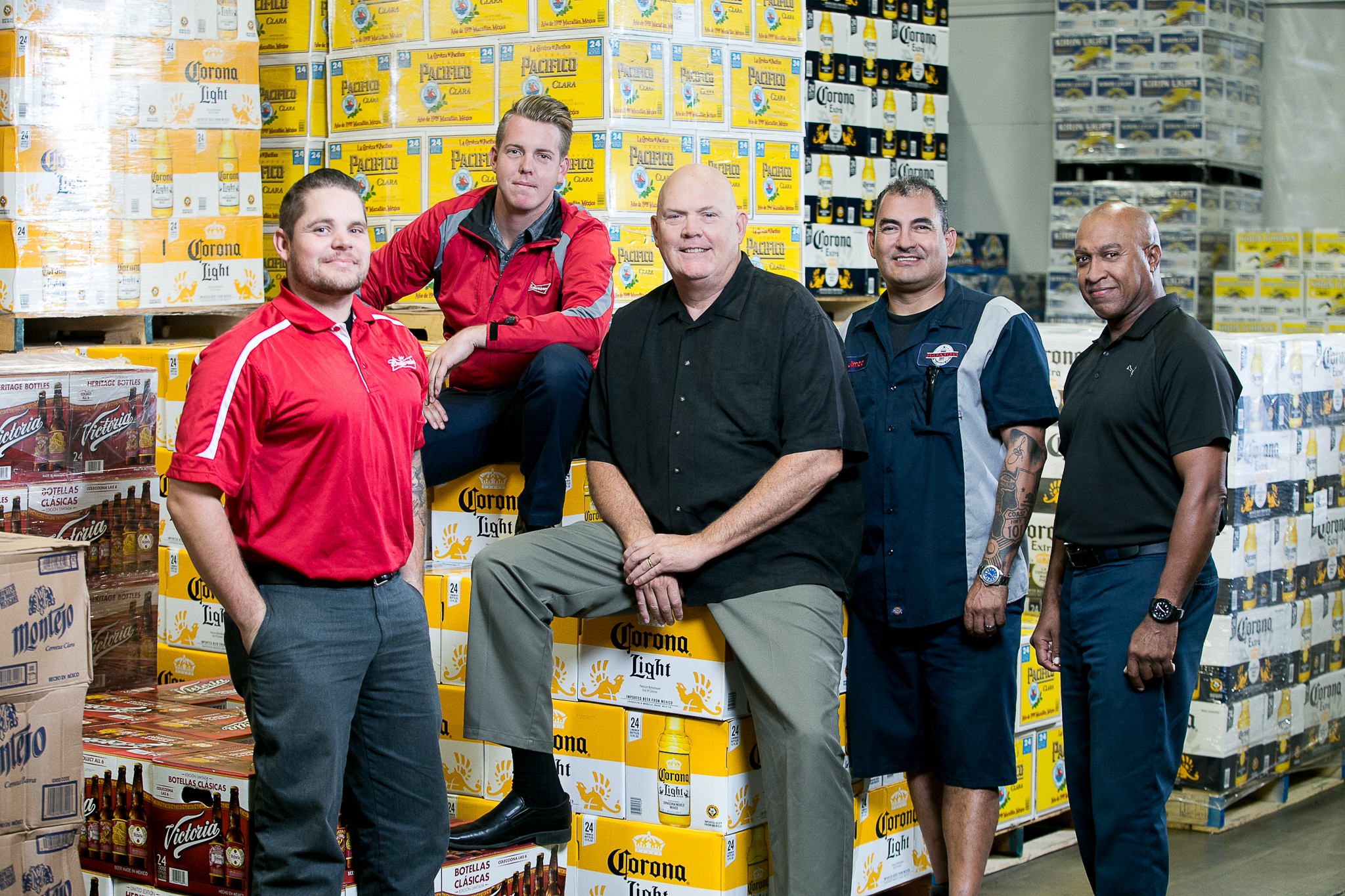 Warehouse team posing in front of stacked beverage cases
