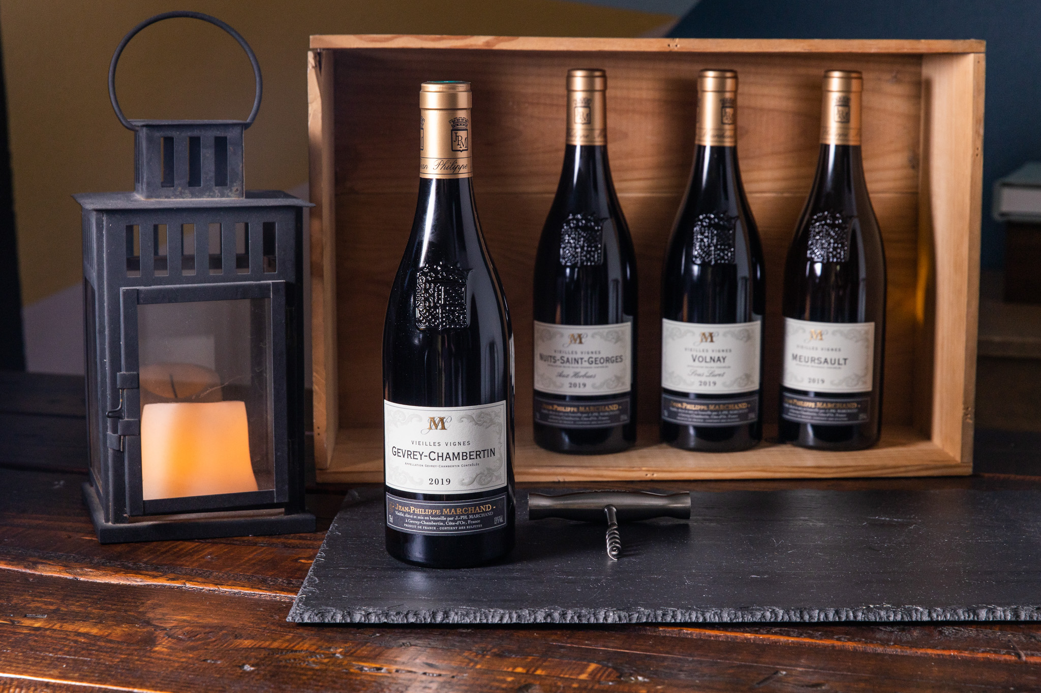Wine bottles displayed in a wooden crate with a lantern