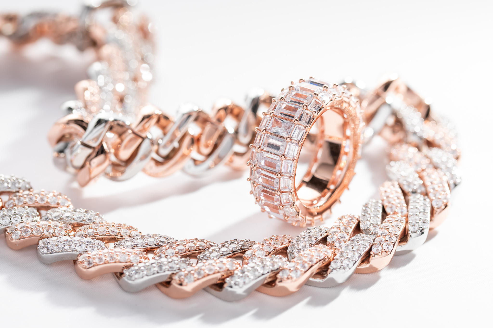 Rose gold and diamond jewelry arranged on a white surface
