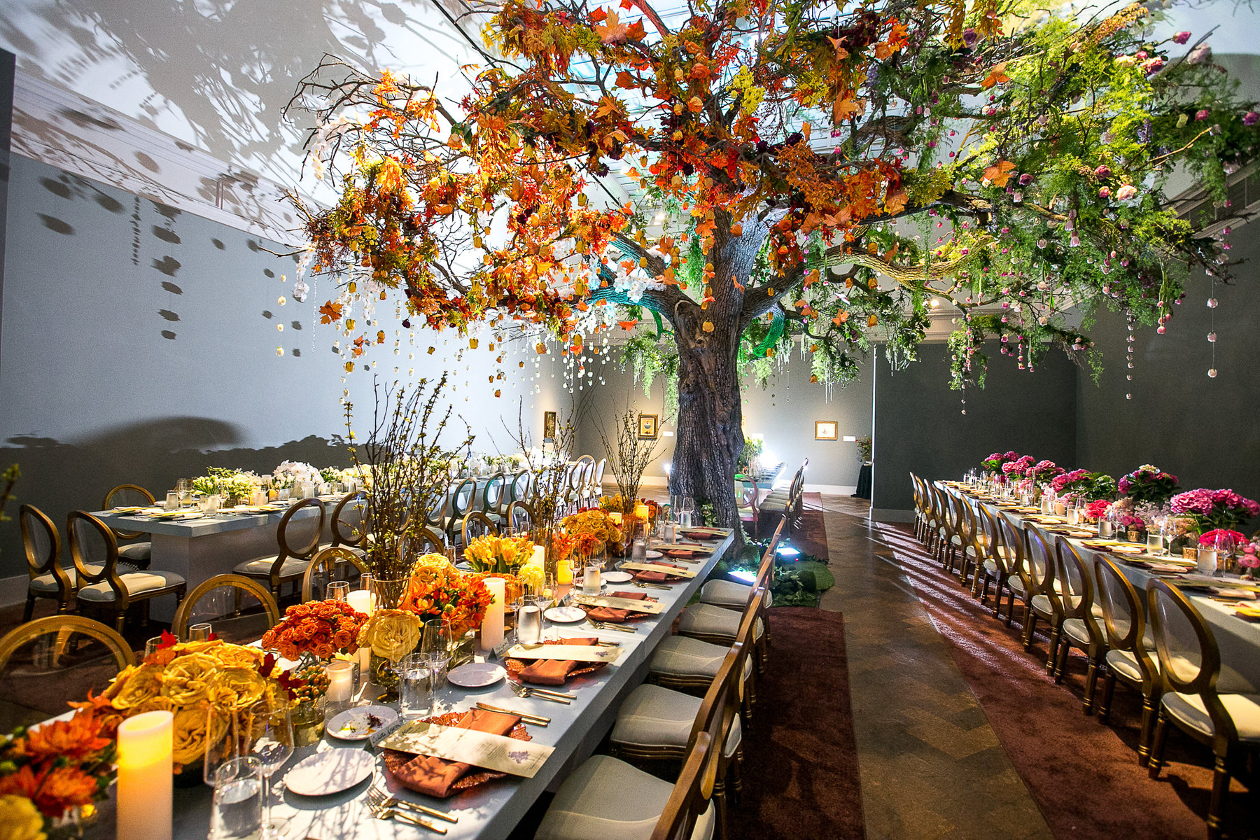 Elegant event tables beneath a large decorative tree
